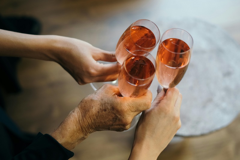 a picture of three different hands holding rose champagne flutes and toasting